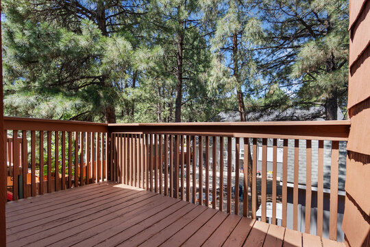 A beautiful wooden deck complete with a railing and trees in the background