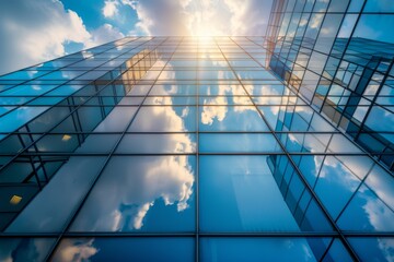 Modern glass building reflecting clouds under bright sunlight