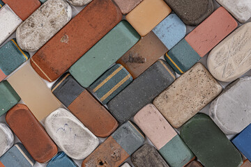 A collection of various used and worn-out erasers, flat lay photograph of a scattered collection of vintage, heavily used, and well-worn rectangular erasers