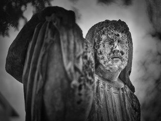 Weathered stone statue at Goat Gate Cemetery in Bratislava, photographed in dramatic black and white.