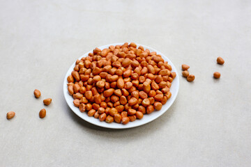 Raw, shelled peanuts piled on a white plate, ready for roasting.