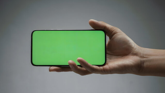 Hand holding horizontal smartphone green screen mockup, chroma key mobile phone template, landscape blank display, isolated grey background, for app, game, video, ux.