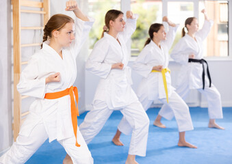 Team of teenage girls in kimonos stand in fighting stance during a group karate training session
