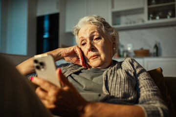 Senior woman looking concerned at smartphone at home