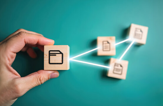 Human hand holds folder icon wooden block. Glowing lines link to document icon blocks. Illustrates data organization, info flow, connection. Concept of digital file management system, cloud storage,