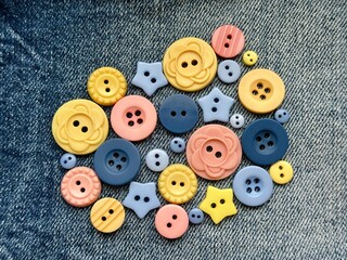 Pink, yellow and blue buttons in different sizes are on the denim background