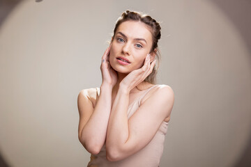 Obraz premium Female model posing with confidence for a cosmetics advertisement, wearing radiant natural makeup in the studio. Graceful positive expression embracing self acceptance and femininity.