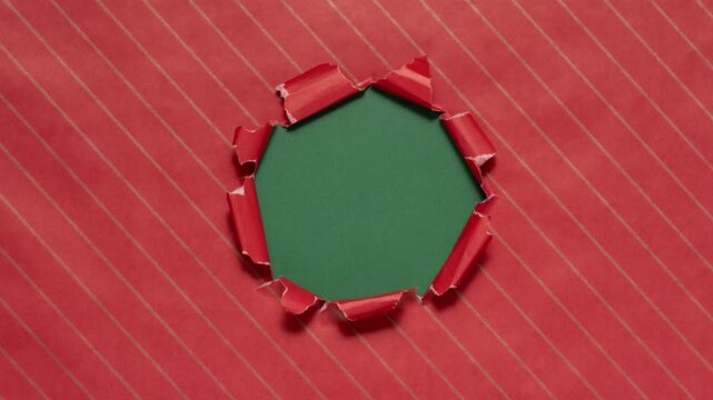 Christmas wrapping paper tears from the center on a green background. Stop motion. Layout for discounts, text, etc