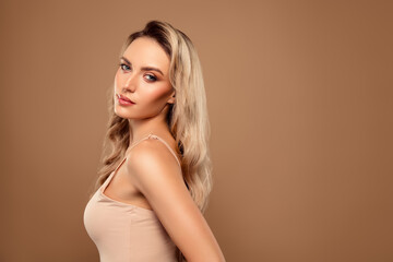 Fototapeta premium Blonde woman posing elegantly against beige background showcasing beauty, style, and charm in a fashion