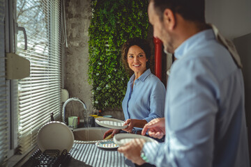 Couple washing dishes together during daily routine