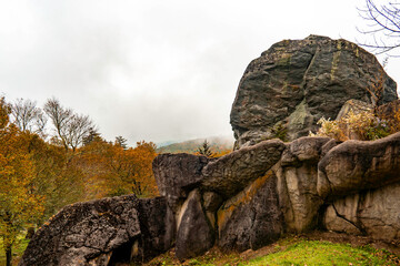damp rocky outcrop with autumn trees, steep stone ledge overlooking fall foliage in damp weather