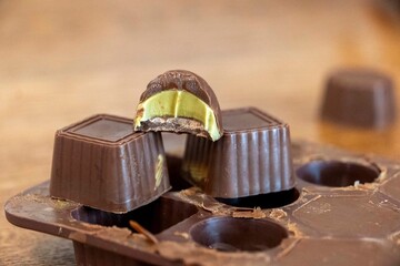 A person is gracefully holding a tray filled with chocolates on a table