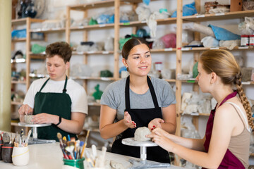 Potter teaches teenagers how to make pottery out of clay in a workshop