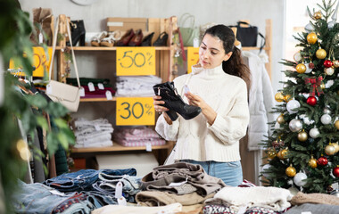 Armenian girl near showcase pick out and buying heeled ankle boots. Off line clothing store from retailer. Style and fashion look, modern trends. Discount X mass holiday season, promotional offers.