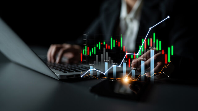 A business professional analyzes financial charts on a laptop in a dark office. The image features stock market data graphics, reflecting investment strategies and growth trends. Scalp - Powered by Adobe