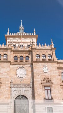 Timelapse of the Cavalry Academy facade in Plaza de Zorrilla, Valladolid, Spain. Historic military building with intricate architecture, surrounded by a busy urban scene under a blue sky with clouds.
