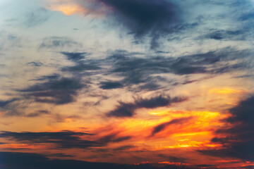 Fiery sunset clouds streak the sky in vivid colors fading into deep blue above. Light and shadow...