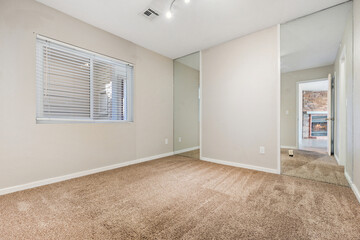 A vacant bedroom featuring a spacious window and a cozy brown carpet