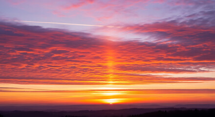 Fototapeta premium Vibrant orange and red sunrise or sunset sky with crepuscular ray