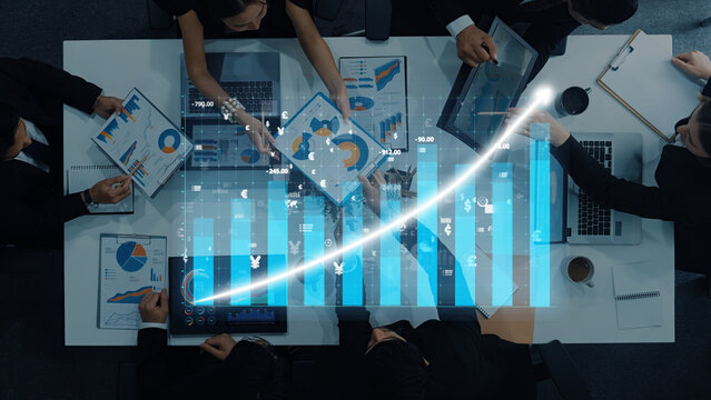 A diverse group of professionals collaborates in a modern office, analyzing financial charts and data visualizations that represent business growth and strategy development. Axiom