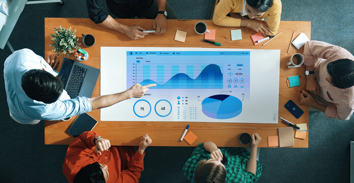 Engaging team meeting focused on data analysis with digital visualization tools on a modern tabletop, showcasing collaboration and innovative thinking in an office. Axiom