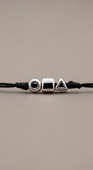 Minimalist Black Cord Bracelet with Geometric Silver Charms on Gray Background.