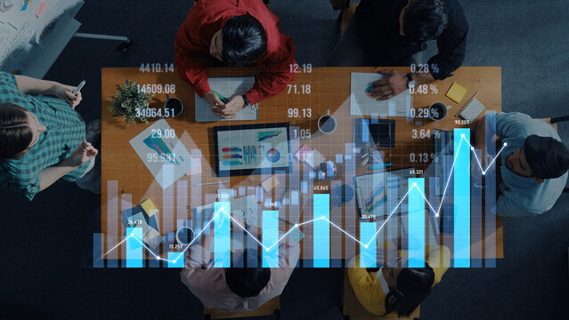 A diverse group of professionals engages in a financial analysis meeting, examining charts and graphs on a desk in a modern office. The scene showcases collaboration and strategic planning. Scalp - Powered by Adobe