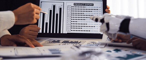 A group of diverse professionals engaged in a business meeting, analyzing product export graphs on a tablet while incorporating technology into their teamwork efforts.Noogenesis