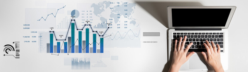 A modern workspace featuring hands on a laptop, with colorful charts and graphs indicating data...