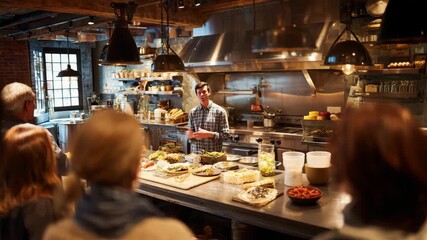 Chef giving a cooking demonstration to a group of people in a restaurant kitchen