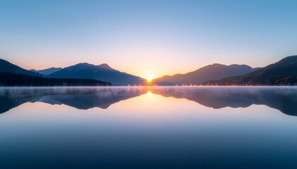 Fototapeta premium 静寂の夜明け：山間に昇る太陽と湖面に映る完璧なシンメトリー