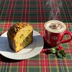 Panettone with pistachios and a red mug of coffee on a plaid tablecloth with holly decoration