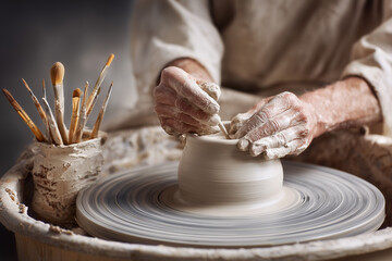 Hands shaping a ceramic pot on a spinning pottery wheel in studio