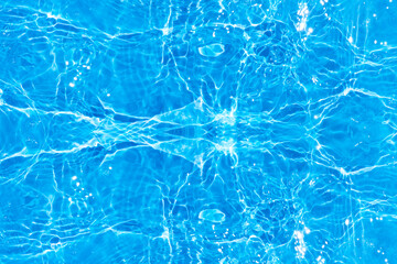 Blue water with ripples on the surface. Defocus blurred transparent blue colored clear calm water surface texture with splashes and bubbles. Water waves with shining pattern texture background.