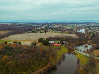 Naklejka premium Aerial drone photo of a lake with a red barn and houses, farm fields in view. 