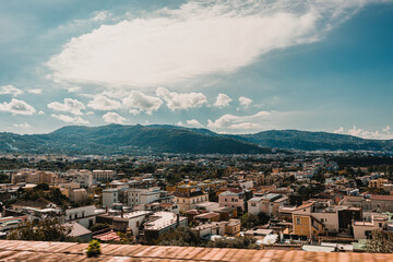 Cityscape view of buildings and residential homes extending towards a massive, green-covered...