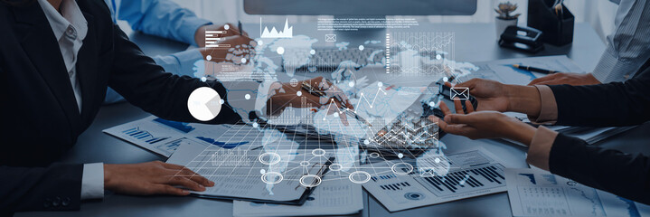 A team of business professionals collaborates around a table, analyzing charts and data to develop strategies for growth and performance improvement using technology. Trope