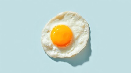 Fried egg. Yolk is sunny-side up on a pale blue background with shadow