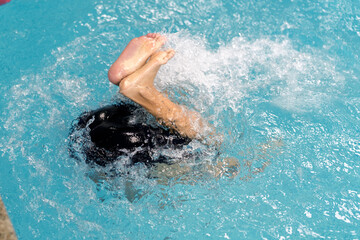 Child learning to swim kicking feet in pool