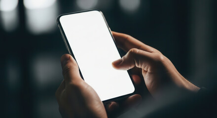 Close-up of man's hands holding a modern smartphone with a blank white screen, perfect for copy space against a dark background.