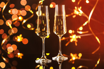Happy New Year. Sparkling wine in flute glasses against sparklers and blurred lights on black background, bokeh effect