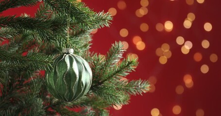 Woman putting beautiful ball on christmas tree against red background, closeup. Bokeh effect - Powered by Adobe