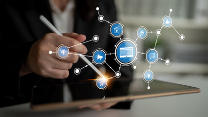 A professional engages with a tablet in a modern workspace, highlighting digital tools and icons that symbolize marketing, communication, and networking strategies. Tessel