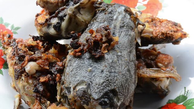 Extreme Close-up Macro Shot of Crispy Fried Catfish Head (Ikan Lele) with Dark Spices and Crunchy Bits. Authentic Asian Street Food and Local Cuisine