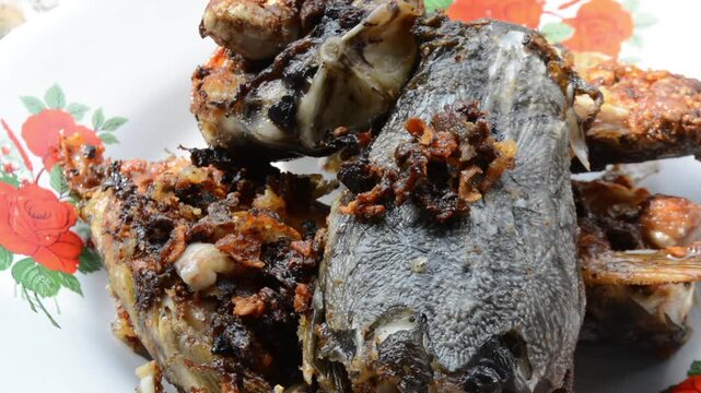 Extreme Close-up Macro Shot of Crispy Fried Catfish Head (Ikan Lele) with Dark Spices and Crunchy Bits. Authentic Asian Street Food and Local Cuisine