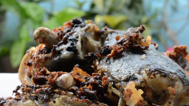 Extreme Close-up Macro Shot of Crispy Fried Catfish Head (Ikan Lele) with Dark Spices and Crunchy Bits. Authentic Asian Street Food and Local Cuisine