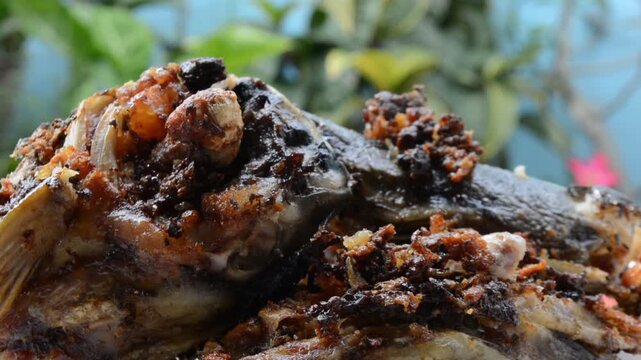 Extreme Close-up Macro Shot of Crispy Fried Catfish Head (Ikan Lele) with Dark Spices and Crunchy Bits. Authentic Asian Street Food and Local Cuisine