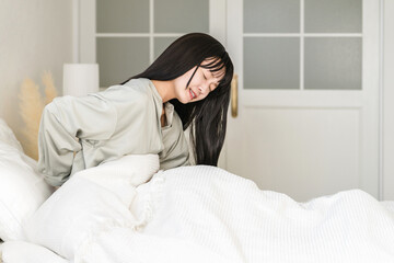 Obraz premium Japanese woman suffering from lower back pain and hernia in the bedroom 