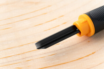 木板と彫刻刀の三角刀の刃先のクローズアップ