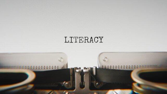 Old mechanical typewriter typing Literacy in a close-up view, with metal letters striking the white paper.